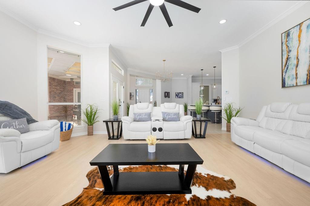Light wood-finish flooring throughout, recessed ceiling lighting, crown molding, and a vaulted ceiling with a ceiling fan
