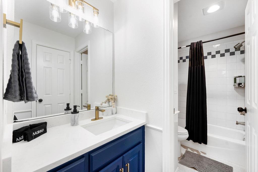 Bathroom featuring a white vanity with a blue cabinet, a single-basin sink, and a gold-finish faucet