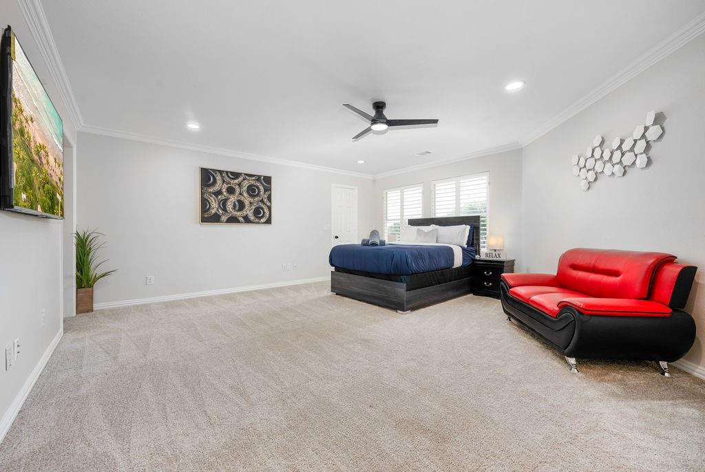 Recessed lighting, crown molding, ceiling fan, and light-toned carpet