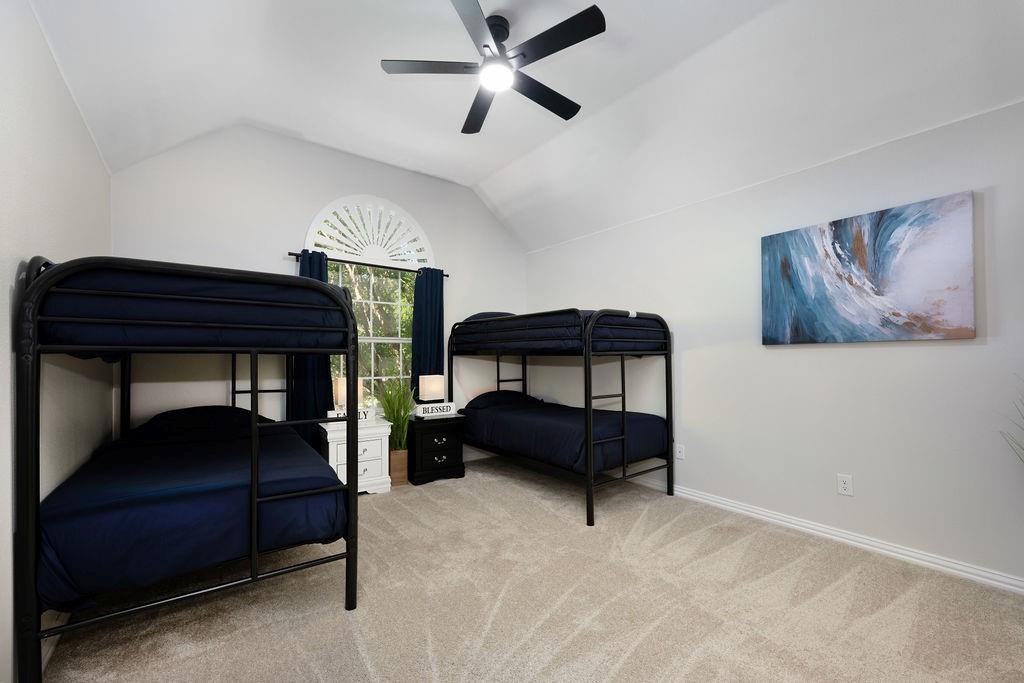 Vaulted ceiling, arched window with decorative fanlight, and a ceiling fan with integrated lighting