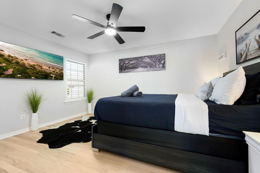 Recessed lighting, wood-finish flooring, white window shutters, ceiling fan with integrated lighting, and a wall-mounted television