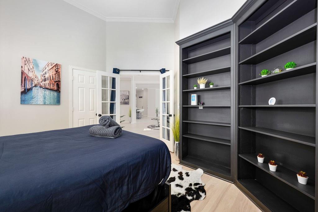 Vaulted ceilings, light wood-finish flooring, built-in shelving, white paneled door, and French doors