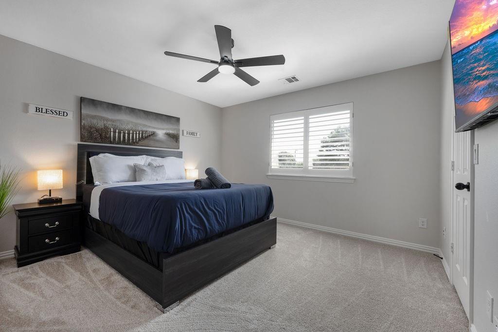 Recessed lighting, ceiling fan with integrated light, carpeted flooring, window with plantation shutters, wall-mounted television
