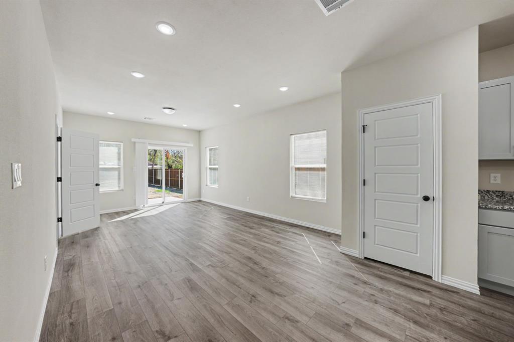 Recessed lighting, wood-finish flooring, sliding glass door, multiple windows, and white cabinetry