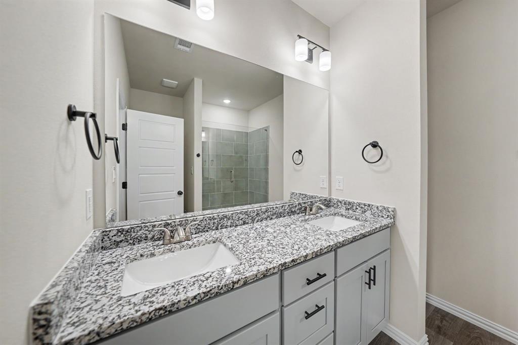 Double vanity with integrated sinks, granite-finish countertop, and undermount cabinetry with matte black hardware