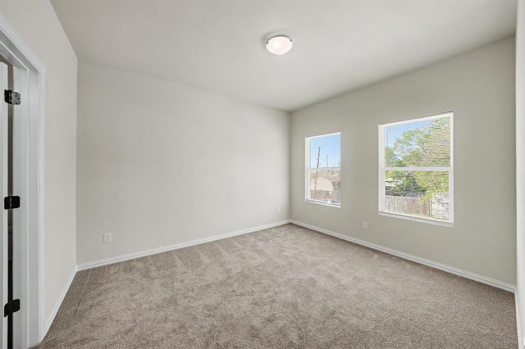 Room featuring light gray carpet, two windows, and a flush mount ceiling light fixture