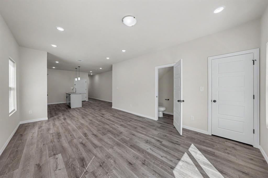 Open-concept layout featuring wood-finish flooring, recessed lighting, white interior doors, and a kitchen island with pendant lighting