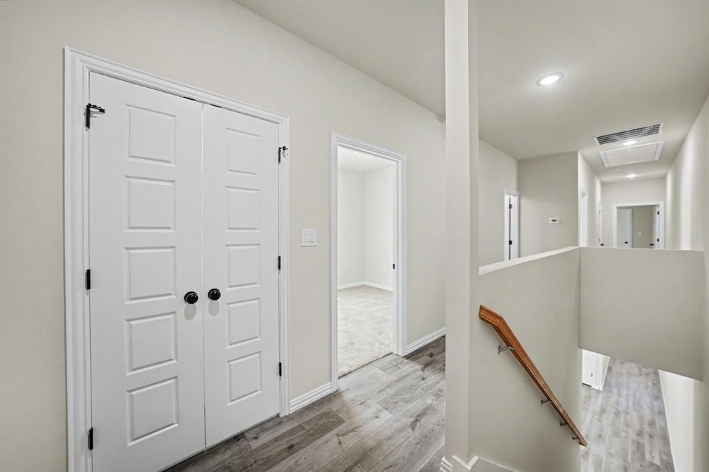 Hallway featuring wood-finish flooring, recessed lighting, and a wood handrail