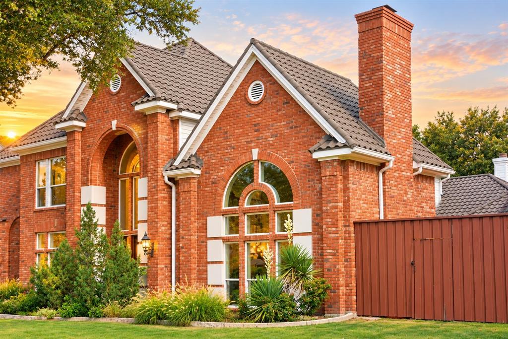 Brick exterior featuring arched windows, a prominent brick chimney, and a tile roof
