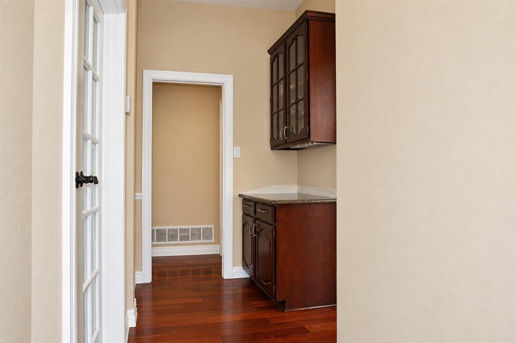 Wood-finish flooring, dark wood cabinetry with glass door accents, and light-toned walls