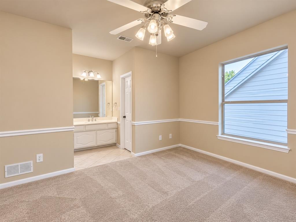 Carpeted room with a ceiling fan light fixture, a large window, and decorative wall molding