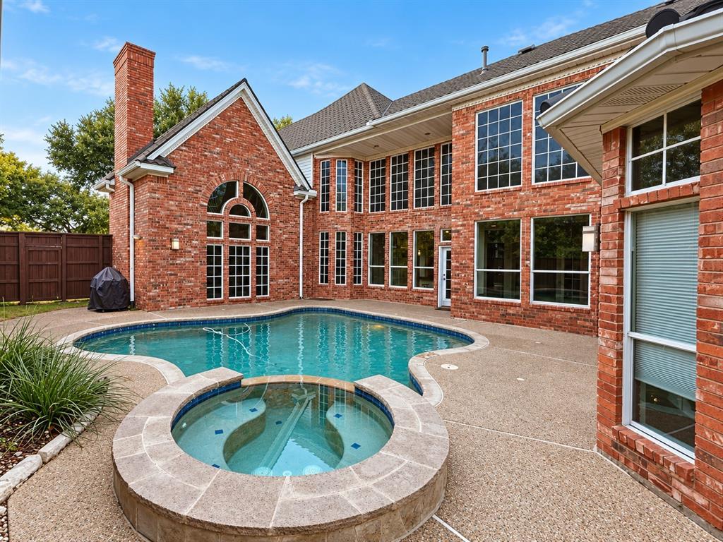 Red brick exterior featuring an in-ground swimming pool, an integrated spa, extensive fenestration, and a stone-clad chimney
