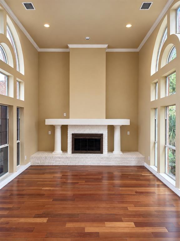 Hardwood flooring with a fireplace featuring a stone surround and mantel