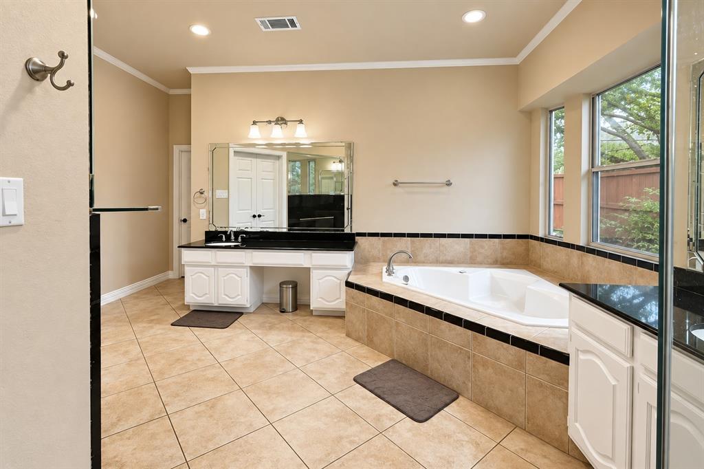 Corner soaking tub with tiled surround, dual windows, and recessed lighting
