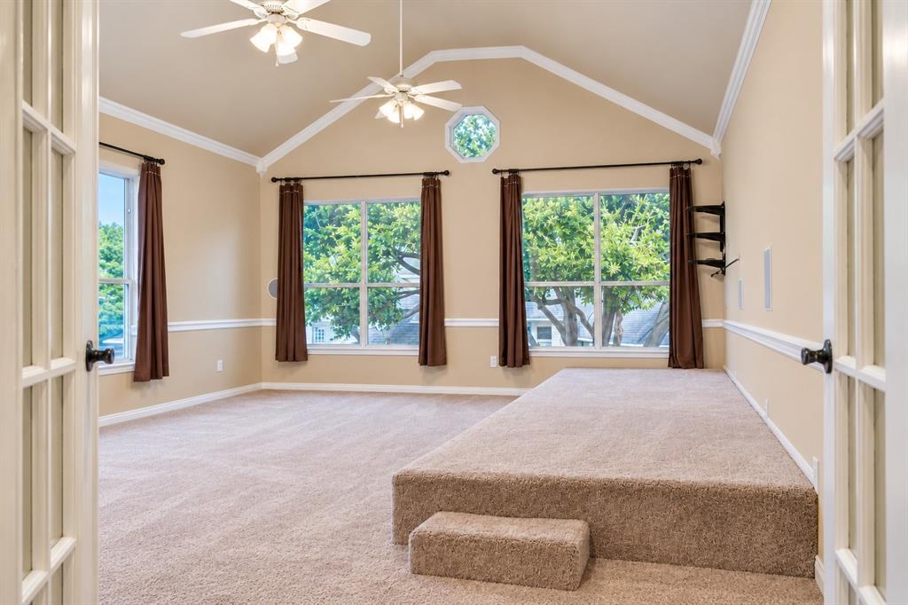 Vaulted ceiling with crown molding, two ceiling fans, and an octagonal window