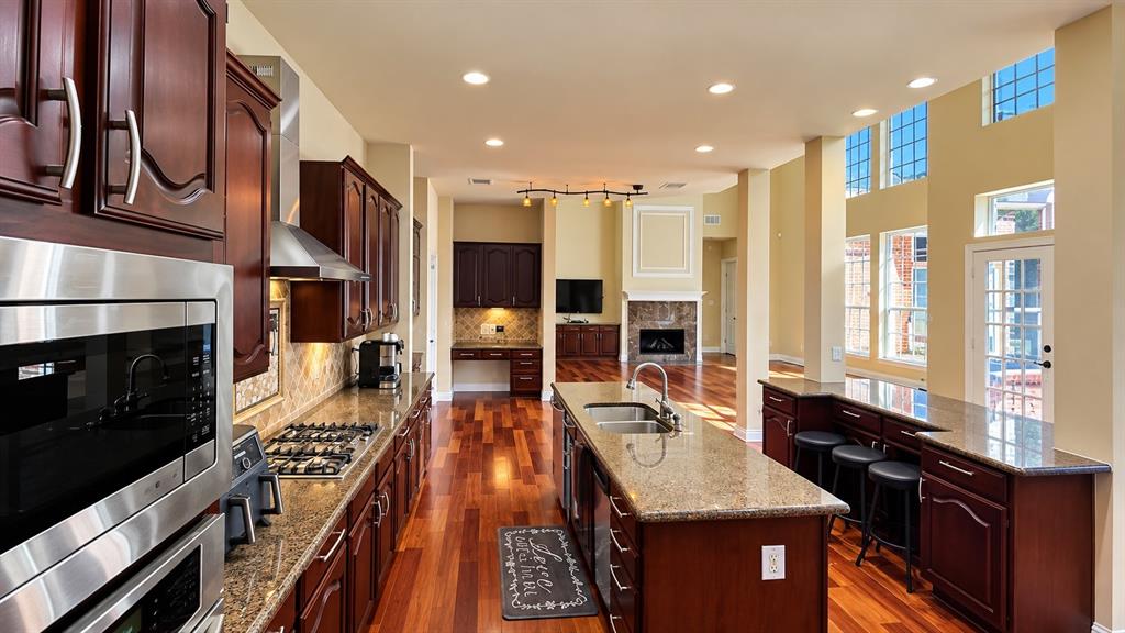 Gourmet kitchen with rich wood cabinetry, stainless steel appliances, and a central island with a built-in sink
