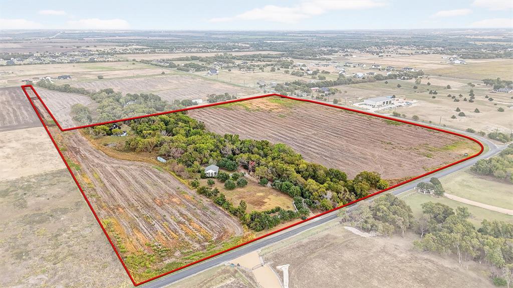Expansive acreage featuring cleared fields, mature tree clusters, and paved road frontage