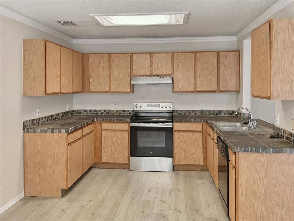 U-shaped kitchen layout featuring wood-finish cabinetry, tile countertops, and a tile backsplash