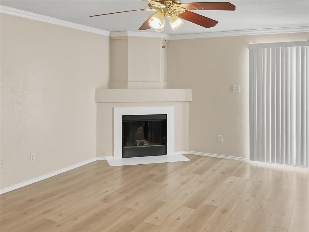 Fireplace with a white mantel, wood-finish flooring, ceiling fan with integrated lighting, and vertical blinds