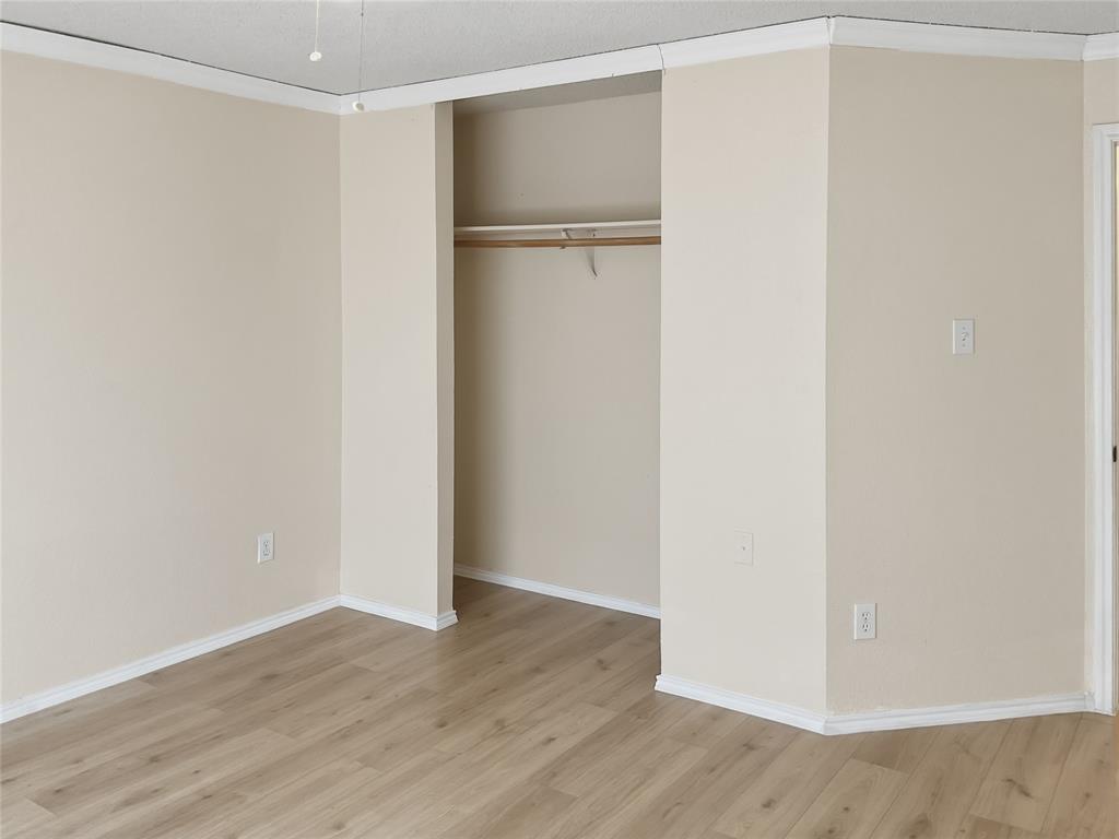 Wood-finish flooring, neutral wall color, and crown molding