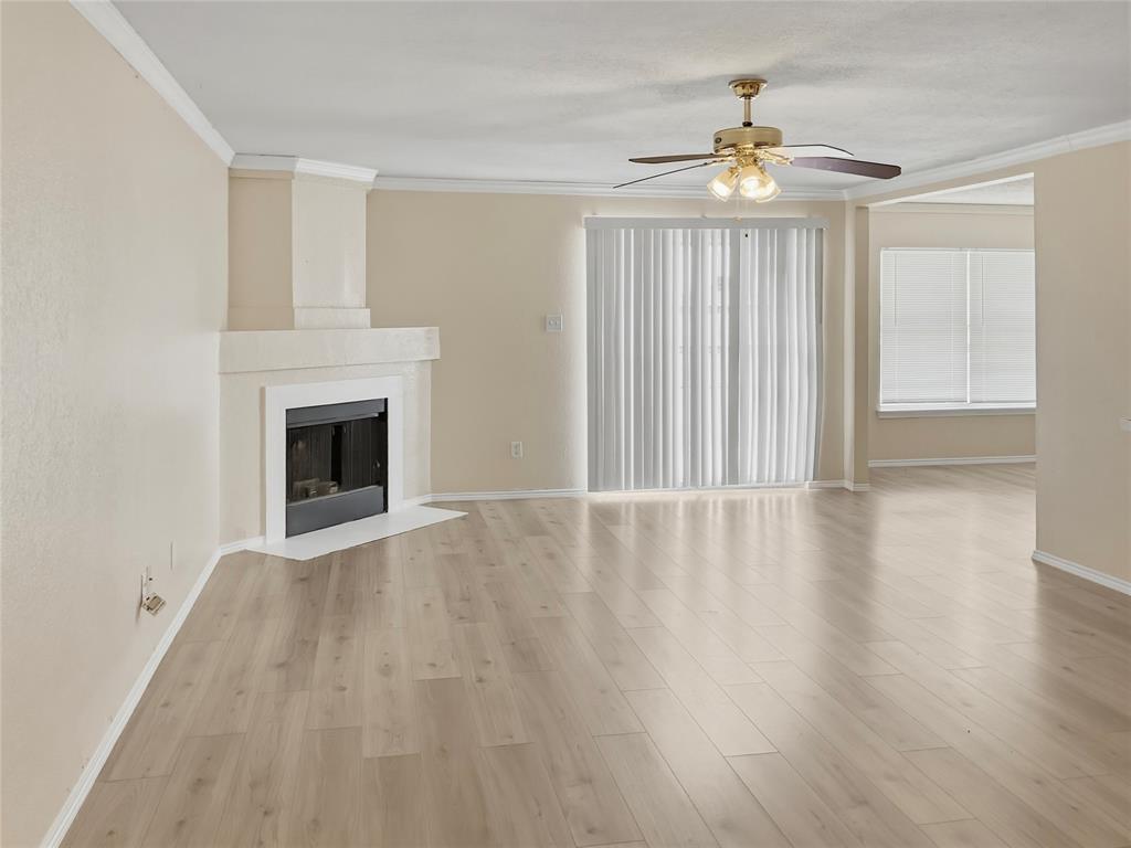 Contemporary fireplace with a hearth, wood-finish flooring, ceiling fan, and crown molding