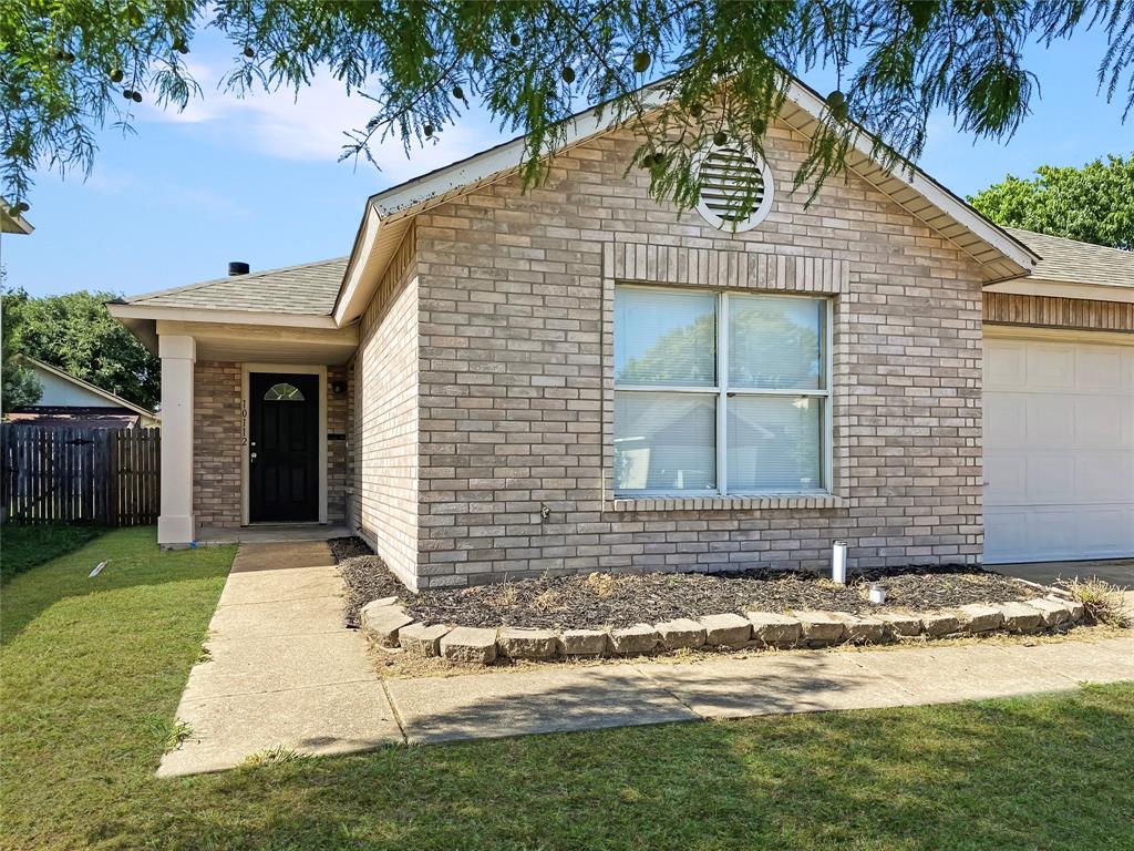 Brick exterior with a covered entry, an attached garage, and a landscaped front yard