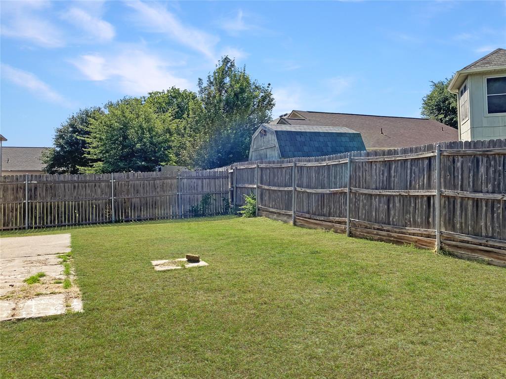 Expansive backyard featuring a wood fence and a concrete patio section