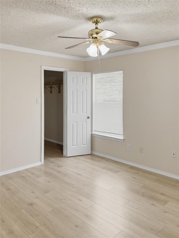 Wood-finish flooring, crown molding, and a ceiling fan with integrated lighting