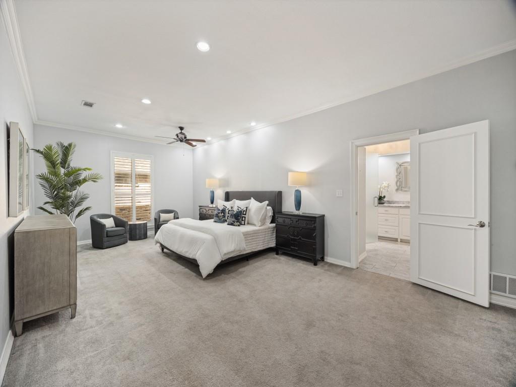 Spacious primary bedroom with crown molding and plantation shutters