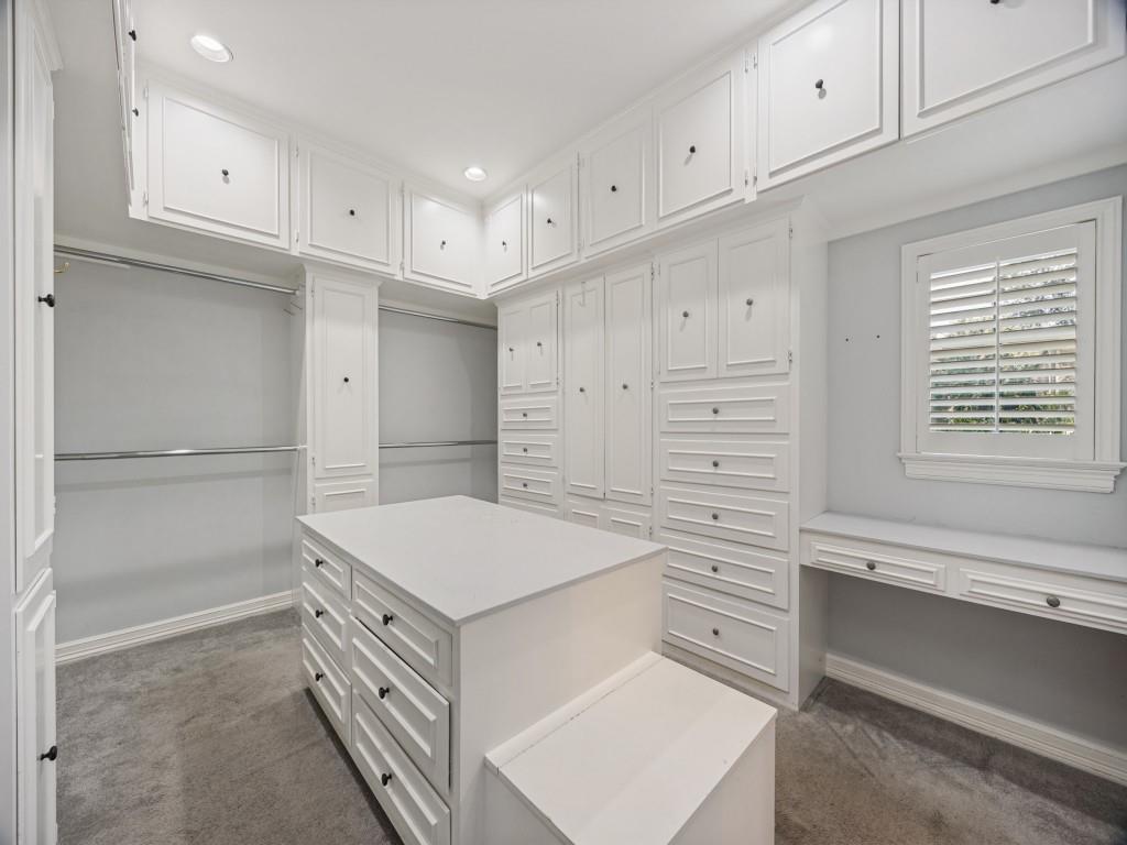Custom primary closet with center island, built-in drawers and vanity