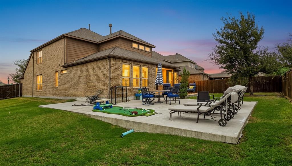 Two-story brick and siding exterior featuring an expansive concrete patio and a fenced backyard