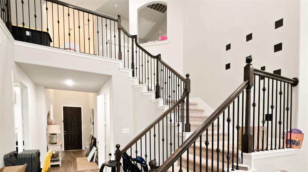 Foyer featuring a two-story ceiling, staircase with dark wood handrails and black metal balusters, and a solid black entry door
