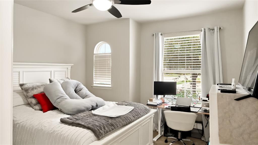 Room featuring an arched window, a multi-blade ceiling fan with integrated lighting, and neutral wall tones