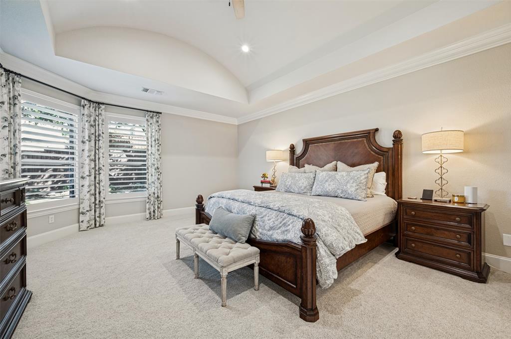 Tray ceiling with recessed lighting, crown molding, double windows with plantation shutters, and light-colored carpeting