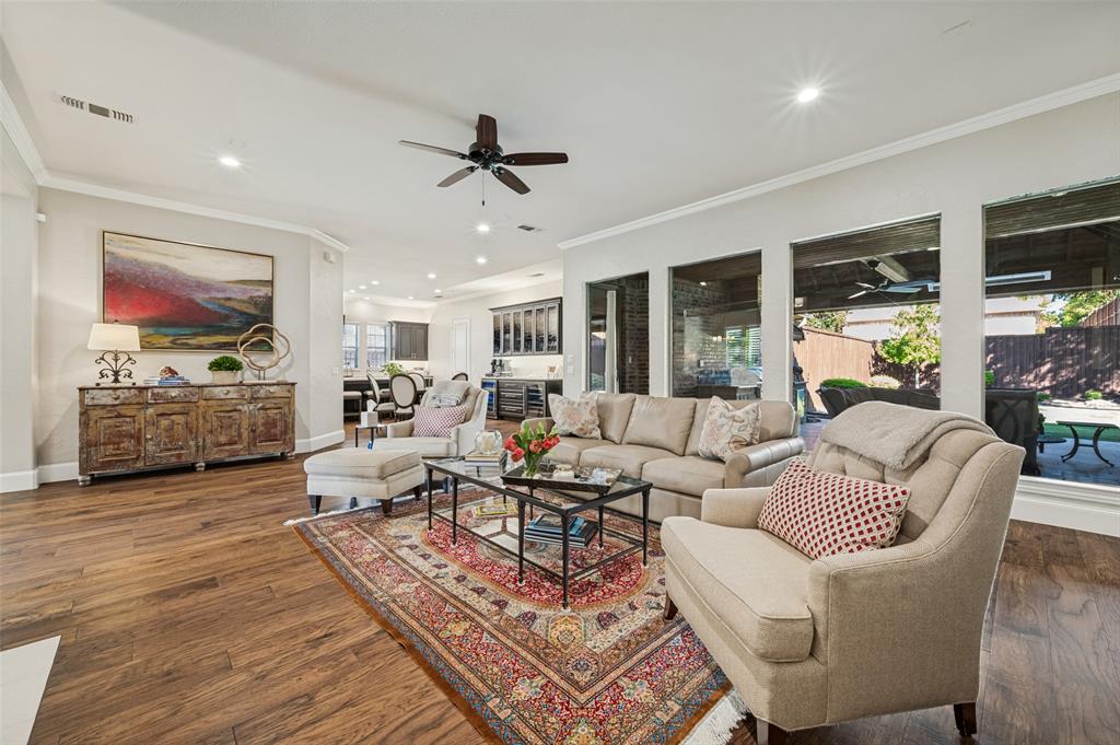 Wood-finish flooring, recessed lighting, crown molding, ceiling fan, and large windows