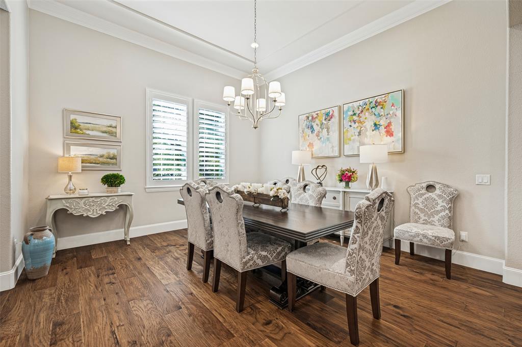Hardwood flooring, crown molding, white plantation shutters, and a classic chandelier