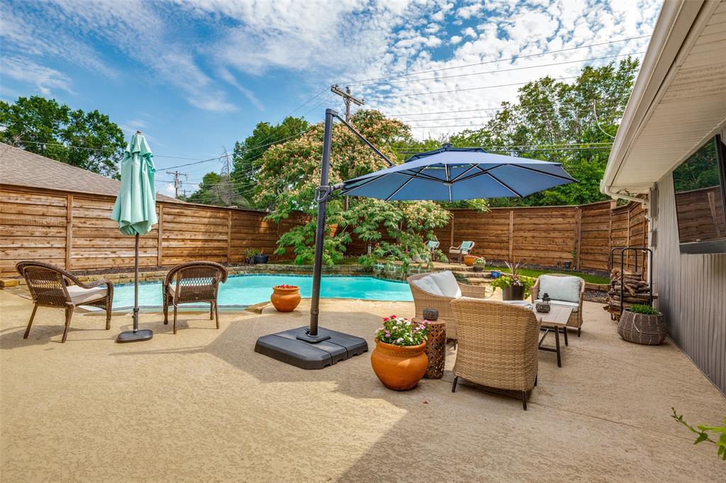 Expansive concrete patio surrounding a swimming pool, bordered by a horizontal plank privacy fence
