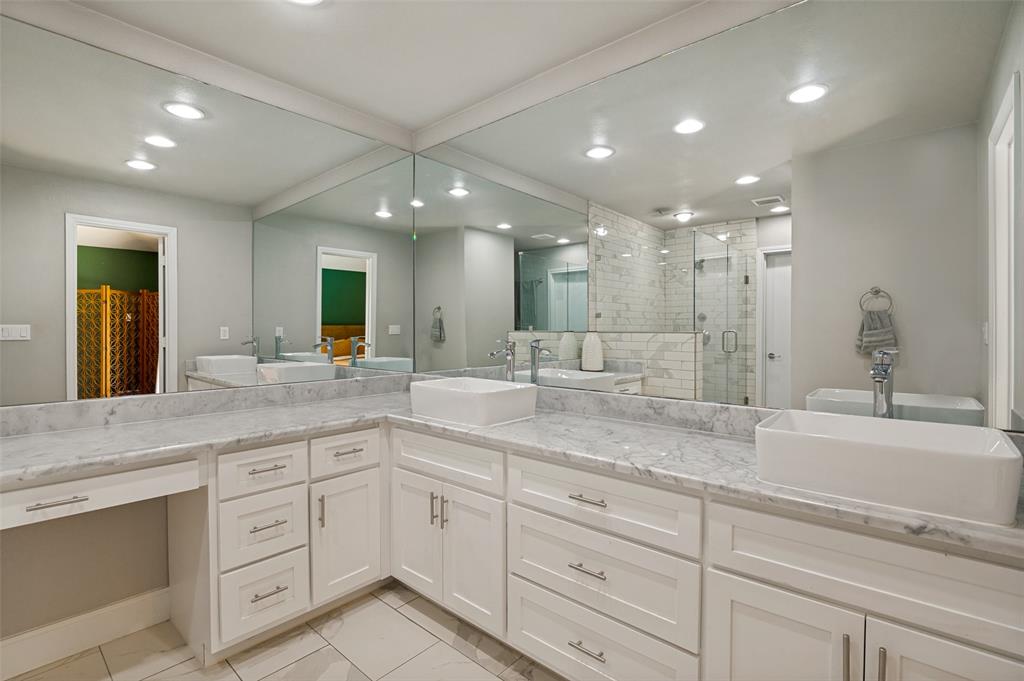 Spacious vanity featuring double vessel sinks, expansive countertop, white cabinetry with brushed nickel hardware, full-height mirror, and recessed lighting