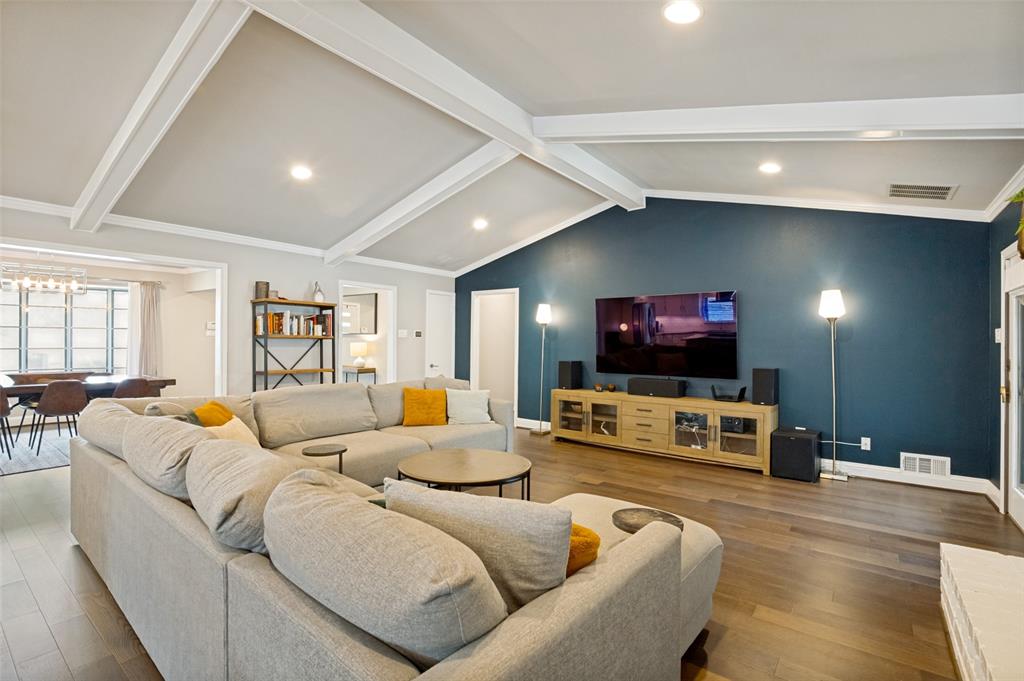 Spacious living area featuring vaulted ceilings with exposed beams, recessed lighting, and wood-finish flooring