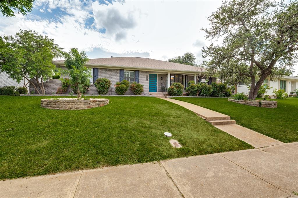 Brick facade residence with a light-colored roof, featuring a vibrant turquoise entry door, blue window shutters, and a covered porch