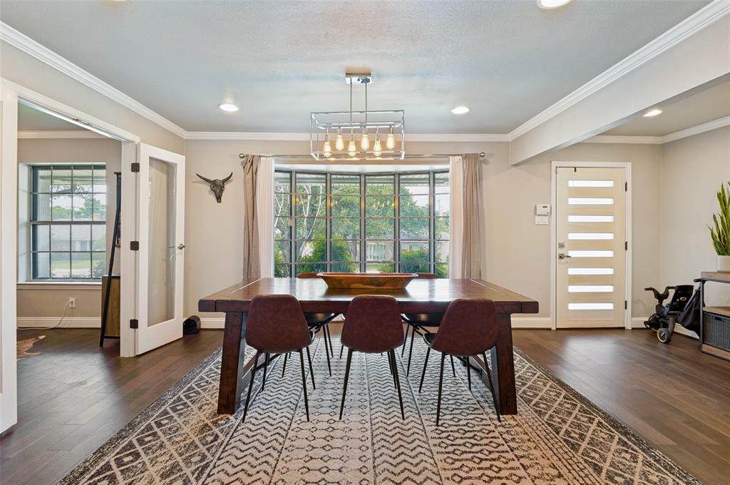 Dining area featuring dark wood-finish flooring, a prominent bay window, and a modern chandelier