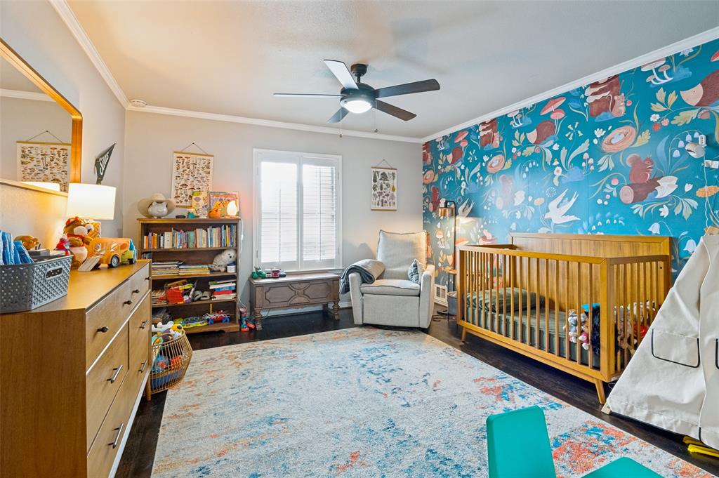 Spacious room featuring dark wood-finish flooring, a ceiling fan, and a prominent accent wall with a detailed pattern