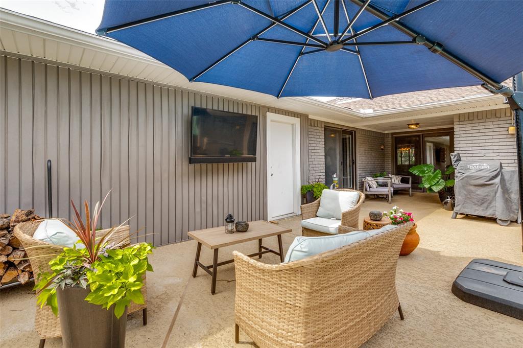 Spacious outdoor patio area featuring a concrete surface, a built-in outdoor television, and a covered ceiling section