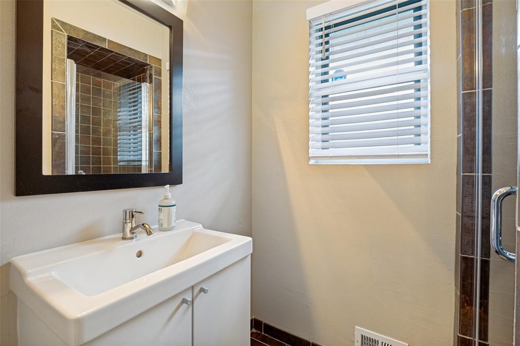 Bathroom vanity featuring a white integrated sink, chrome faucet, and a dark-framed mirror