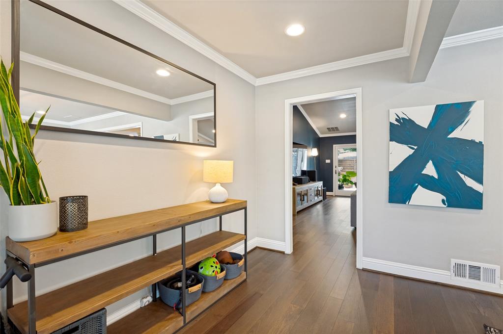 Hardwood flooring extends throughout this entryway featuring recessed lighting, crown molding, and an accent wall