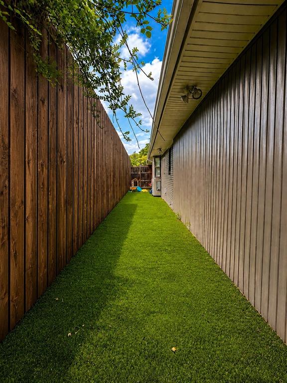 Side yard featuring artificial turf and wood plank fencing
