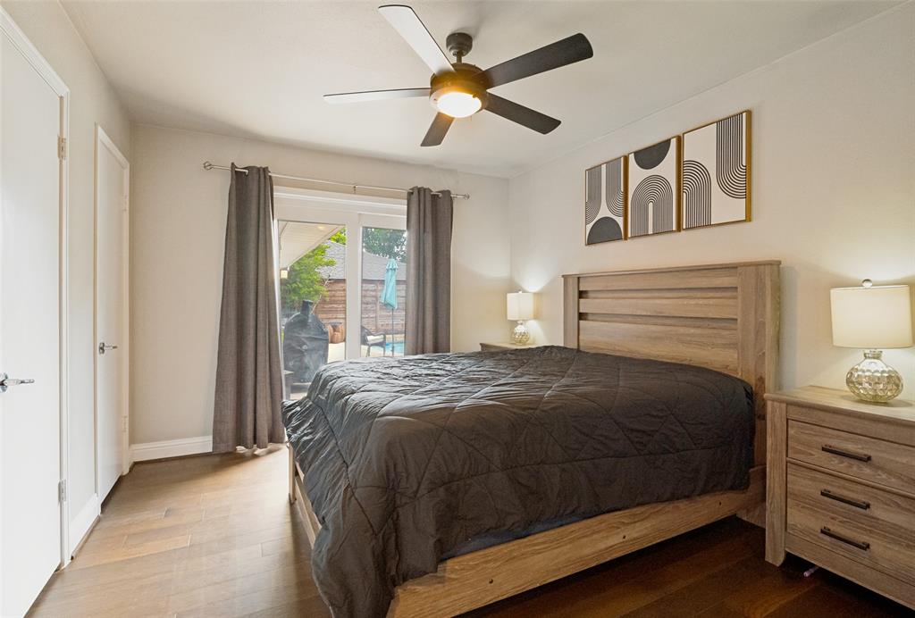 Spacious bedroom featuring wood-finish flooring, a contemporary ceiling fan with integrated lighting, and a private patio entrance