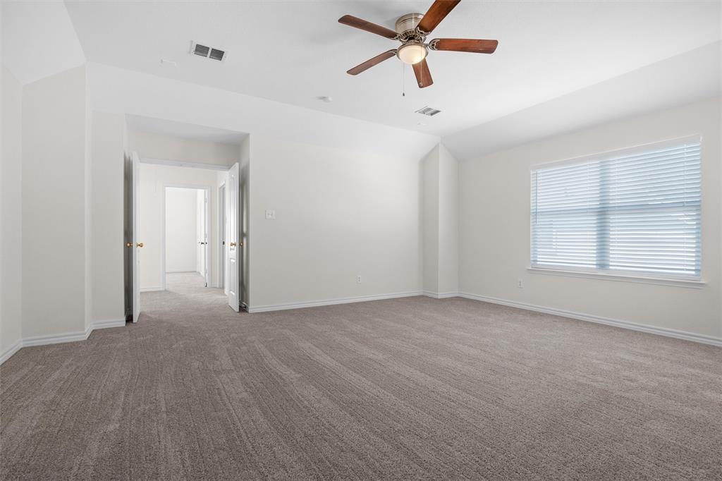 Spacious room with plush carpeting, a large window, a ceiling fan with integrated lighting, and multiple interior doorways