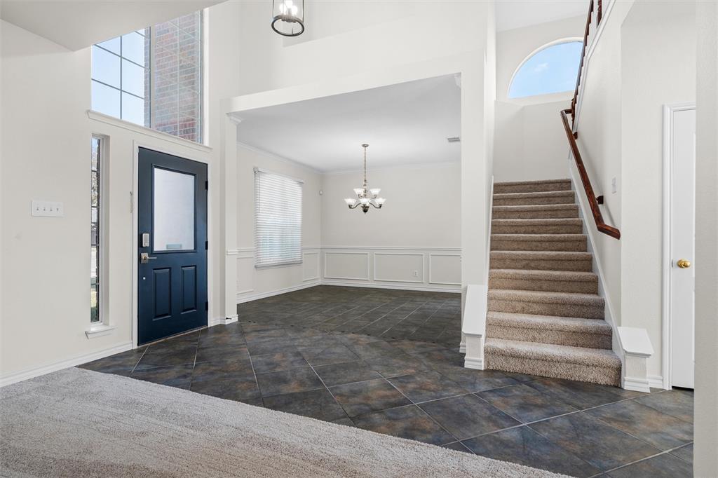 Two-story foyer with high ceilings, dark tile flooring, and an arched transom window