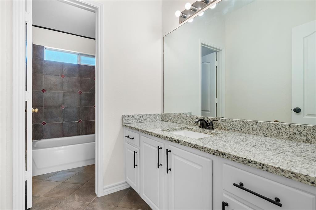 White vanity with dual sinks, speckled countertop, and dark hardware
